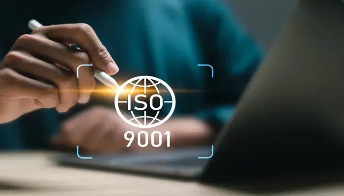 A person using a stylus on a tablet, with the ISO 9001 logo superimposed, representing quality management standards.