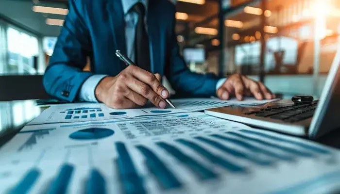 Businessman reviewing charts and graphs on asset management at a desk with a laptop