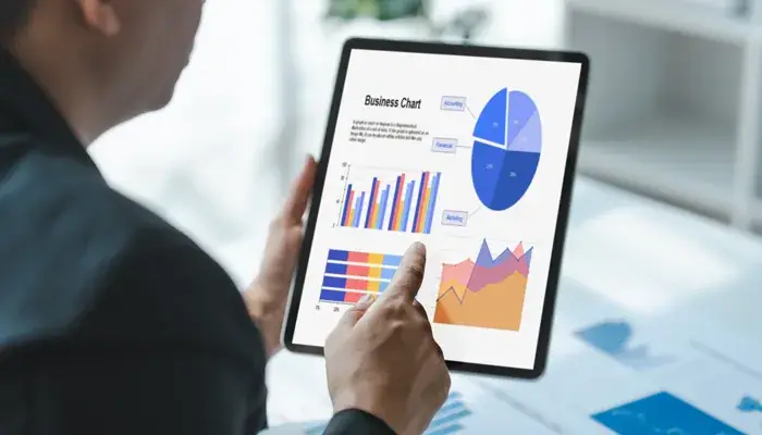 A person holding a tablet displaying various business charts and graphs related to risk indicators.