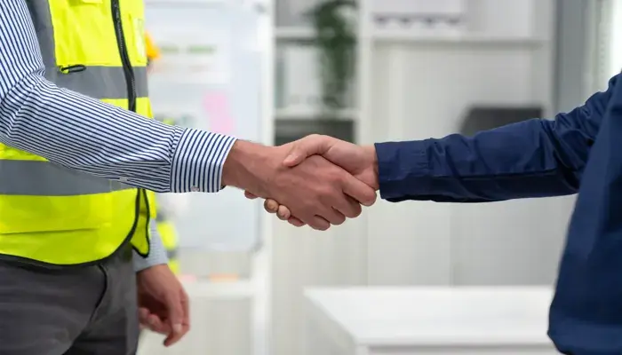 Shaking hands to visualize the value of good communication and the use of workplace safety quotes to enhance safety in workplaces and protect workers