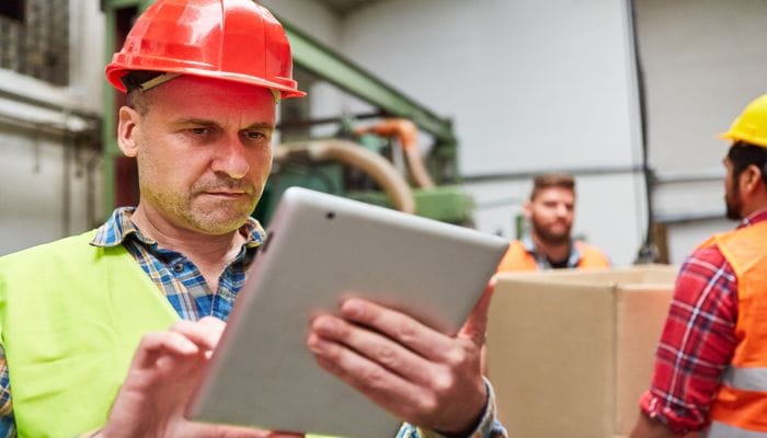 Mitarbeiter mit Tablet bei der Wareneingangskontrolle in einer Fabrikhalle