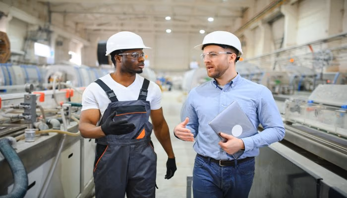Two engineers discussing machine commissioning checklist in an industrial manufacturing facility
