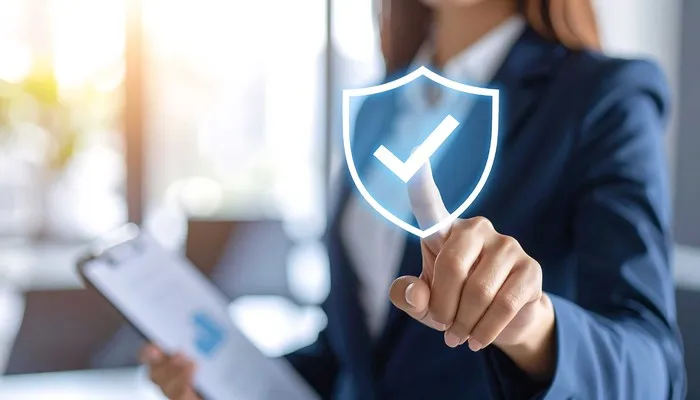 Business professional pointing at a virtual shield with a checkmark symbol on a touch interface, representing structured oversight with the best compliance management software.