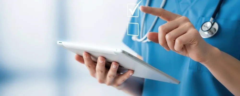 Krankenpflegerin oder Arzt in blauer Schutzkleidung tippt auf einem Tablet, auf dem digitale Checklisten sichtbar sind, Symbol für Checklisten Software für das Gesundheitswesen und Gesundheits-app
